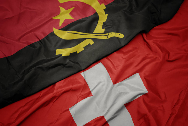 waving colorful flag of switzerland and national flag of angola. - Photo, Image