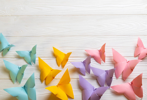 Fondo de madera blanco con brillantes mariposas de origami de papel de colores con espacio de copia para su texto
 - Foto, Imagen