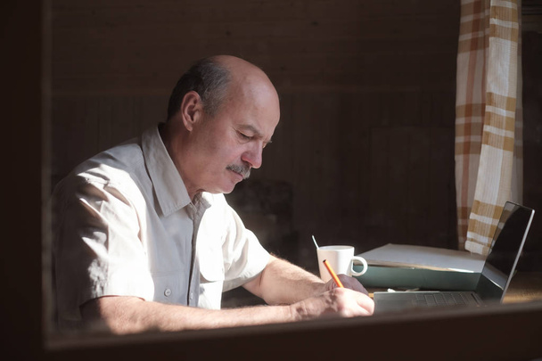 Ένας Ισπανόφωνος που κάθεται κοντά στο παράθυρο και γράφει στο ημερολόγιό του. - Φωτογραφία, εικόνα