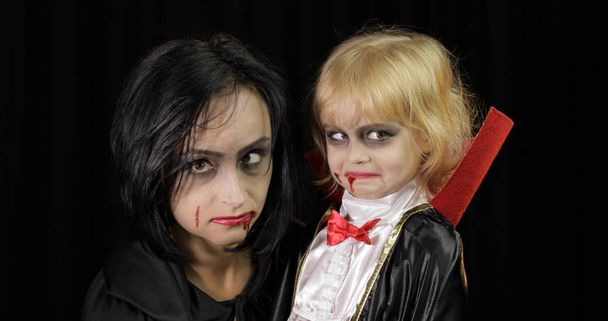 Drácula de mulher e criança. Maquiagem de vampiro de Halloween. Miúdo com sangue no rosto.
 - Foto, Imagem