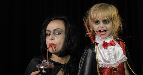 Vrouw en kind dracula. Halloween vampier make-up. Kind met bloed op haar gezicht - Foto, afbeelding