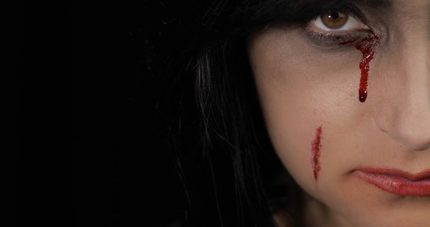 ヴァンパイアハロウィーンの女性の肖像画。目の近くに血を垂らす吸血鬼の少女 - 写真・画像