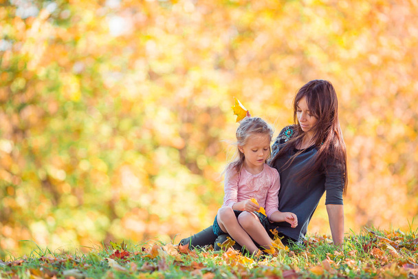 klein meisje met mam buiten in park in de herfst dag - Foto, afbeelding