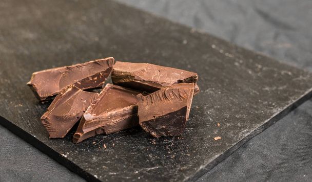 Chocolate con chispas de chocolate sobre fondo negro
. - Foto, Imagen