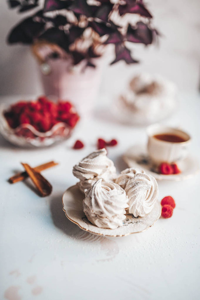 Still life of the homemade Marshmallow zephyr on plate with raw raspberries and a cup of tee on a white table. - Foto, Imagem
