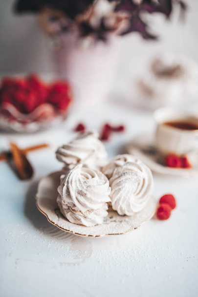 Still life of the homemade Marshmallow zephyr on plate with raw raspberries and a cup of tee on a white table. - Fotografie, Obrázek