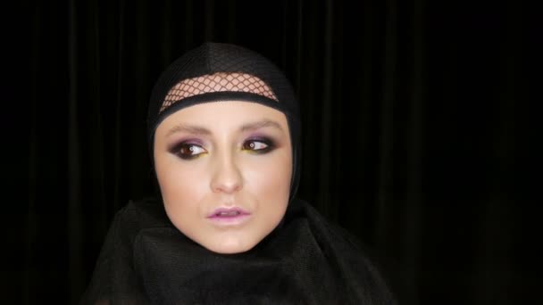 Professional tyttö malli kaunis meikki poseeraa musta lippis päähänsä kameran edessä mustalla taustalla kuvan musta leski. Huippumuoti
 - Materiaali, video