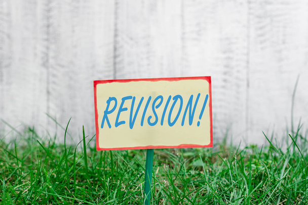 Writing note showing Revision. Business photo showcasing action of revising over someone like auditing or accounting Plain paper attached to stick and placed in the grassy land. - Photo, Image