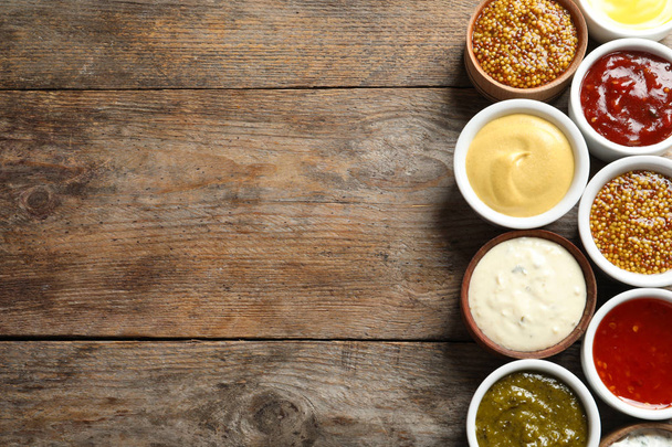 Set of different delicious sauces on wooden table, top view. Space for text - Valokuva, kuva