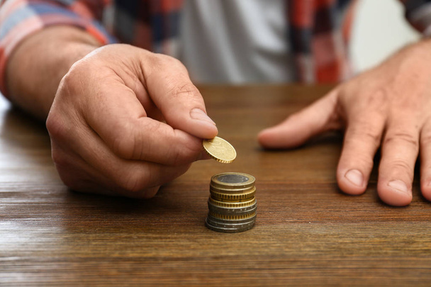 Senior man stacking up coins at table, closeup - Фото, зображення