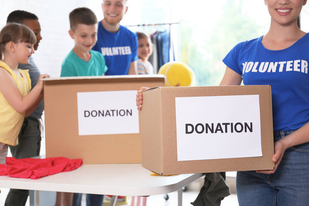 Volunteers with children sorting donation goods indoors - Valokuva, kuva