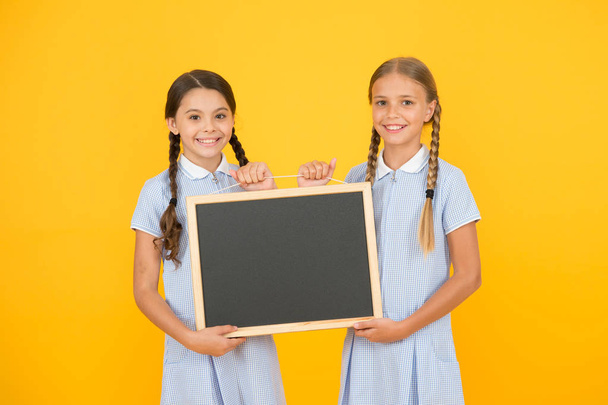 cheerful friends in retro uniform. vintage kid fashion. back to school. small girls hold blackboard. children education. girls presenting information. old school. copy space on board. advertising - Photo, image