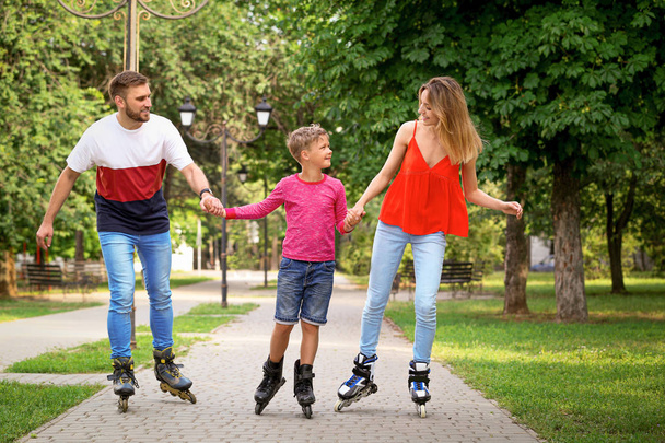 Young happy family roller skating in summer park - Valokuva, kuva