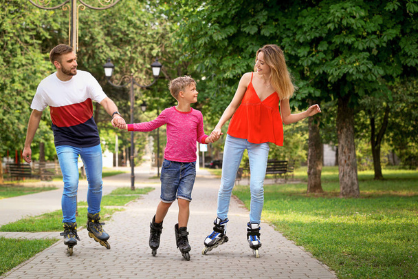 Young happy family roller skating in summer park - Fotografie, Obrázek