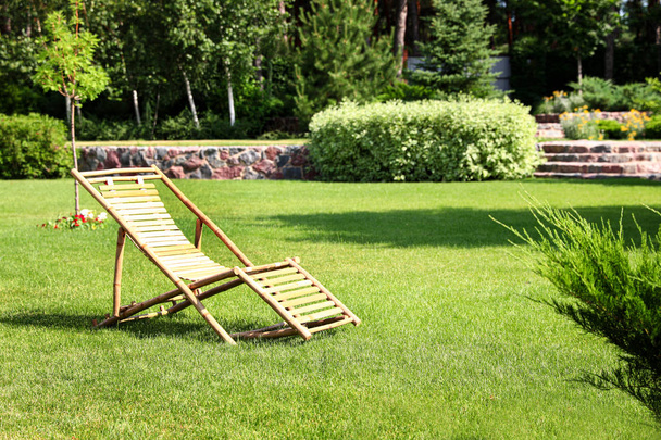 Деревянный шезлонг в красивом саду в солнечный день
 - Фото, изображение