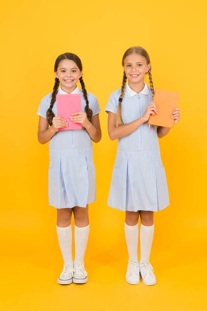 Educational books for schools. Reading books. School library. Homeschooling concept. Literacy club. Cute children holding books on yellow background. Little girls with encyclopedia or childrens books - 写真・画像