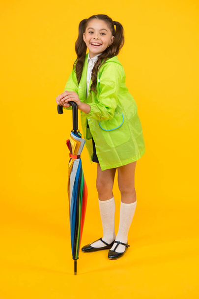 Täysin valmis. Koulutyttö, jolla on sateenvarjo, käyttää vedenpitävää sadetakkia. Syksyn sade. Menen kouluun. Vedenkestävät vaatteet. Suojeltu käsite. Sateenkestävät vaatteet. Syksyn asuste. Syksyn sää
 - Valokuva, kuva