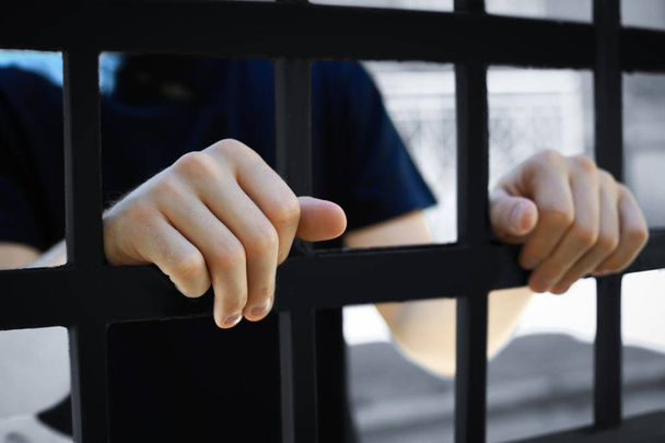 Man opgesloten in de gevangenis buitenshuis, close-up. Strafrecht - Foto, afbeelding