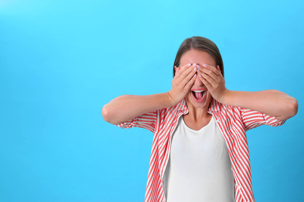 Young woman covering eyes with hands on blue background. Space for text - Fotografie, Obrázek