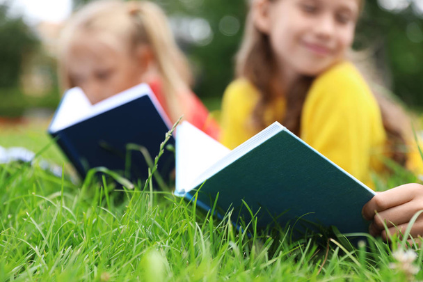 Little children reading books on green grass, closeup - Фото, изображение