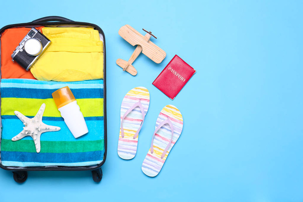 Open suitcase and beach objects on blue background, flat lay. Space for text - Fotografie, Obrázek