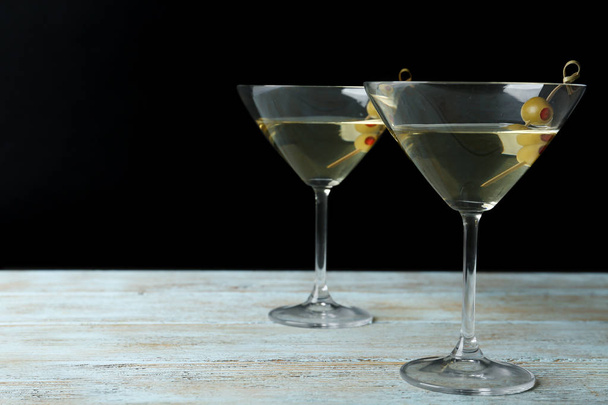 Glasses of Classic Dry Martini with olives on wooden table against black background. Space for text - Zdjęcie, obraz