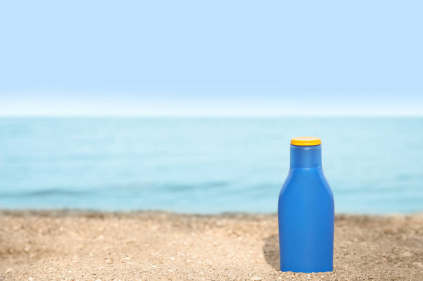 Bottle of sun protection body cream on beach, space for design - Photo, Image