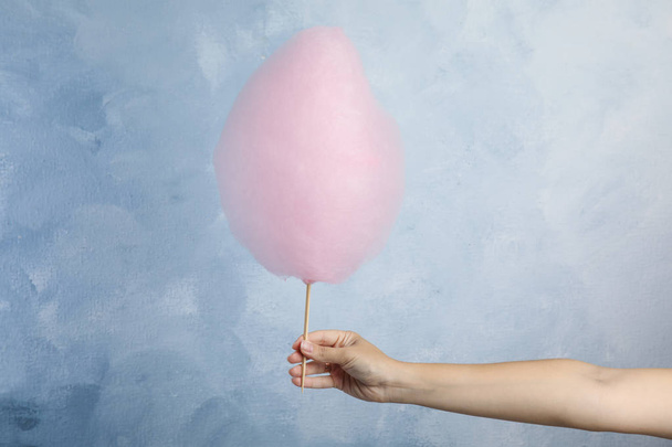 Woman holding sweet pink cotton candy on light blue background, closeup view - Foto, immagini