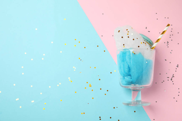 Glass with cotton candy and macaroon on color background, top view. Space for text - Fotografie, Obrázek