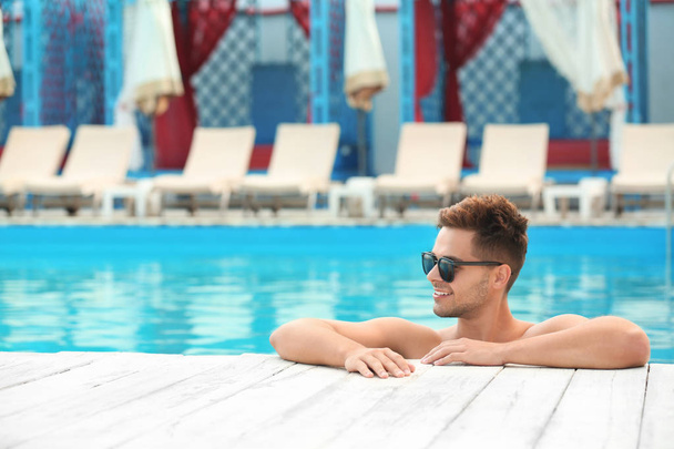 Handsome young man in swimming pool on sunny day - Foto, Imagen