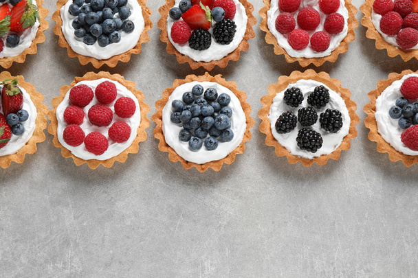 Many different berry tarts on table, flat lay with space for text. Delicious pastries - Foto, Imagem