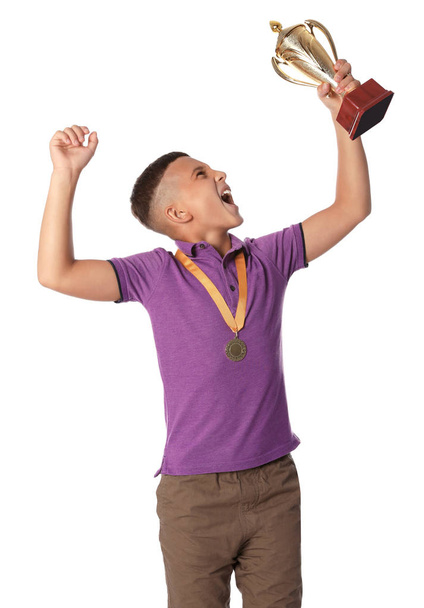 Happy boy with golden winning cup and medal on white background - Φωτογραφία, εικόνα