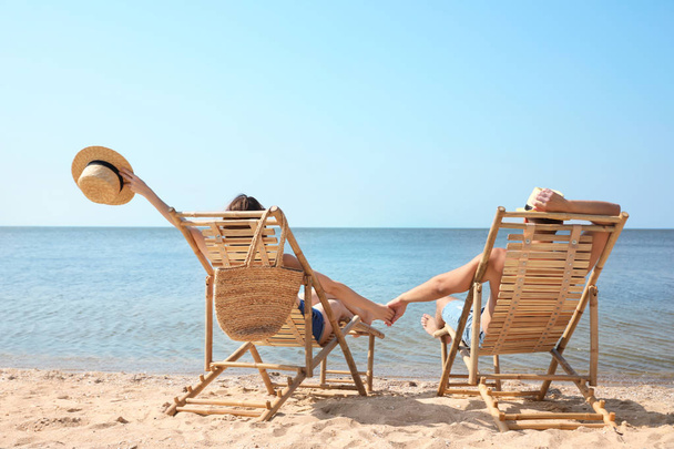 Young couple relaxing in deck chairs on beach - Фото, зображення
