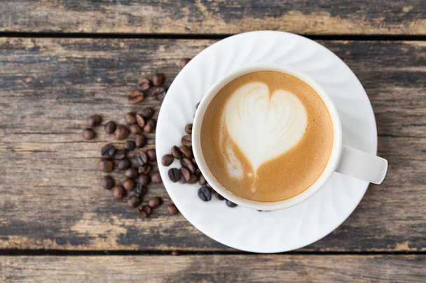 eski ahşap arka plan üzerinde kahve fincanı latte sanat. üst görünüm - Fotoğraf, Görsel