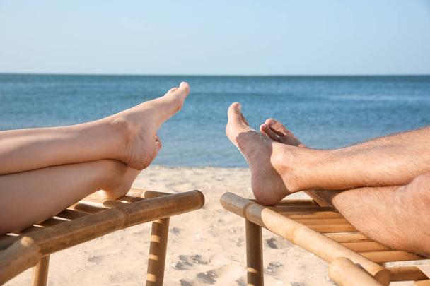 Young couple relaxing in deck chairs on beach near sea, closeup - Фото, изображение