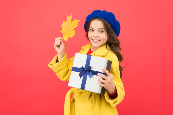 Black friday. Small girl fall outfit red background. Little girl and gift box. Kid hold autumn maple leaf. Child got present. Autumn shopping. Seasonal sale. Received with thanks. Gifts of autumn - 写真・画像