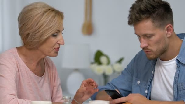 Son ignoring live communication with mother, chatting on smartphone, conflict - Video
