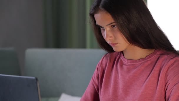 brunette student in purple sweatshirt types on modern laptop - Filmati, video