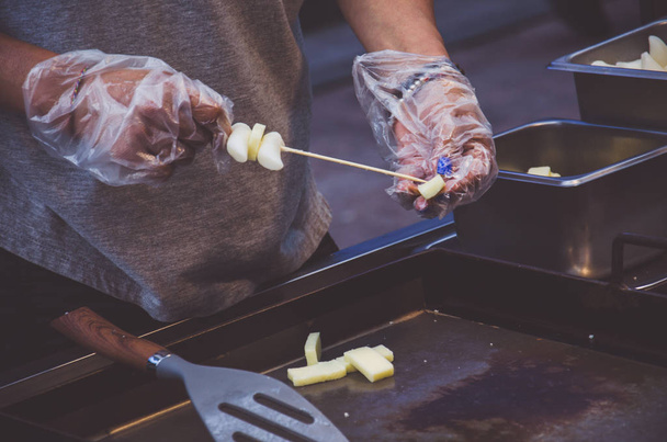 Street food. Mans hands put dough in skewer - Foto, Bild
