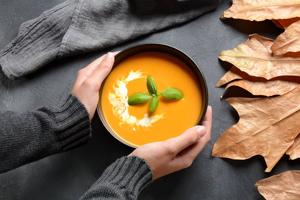 Bowl of pumpkin and carrot cream soup in hands. Autumn hot vegan soup concept - 写真・画像