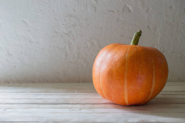 orange pumpkin on wooden table on background old white wall - Foto, afbeelding