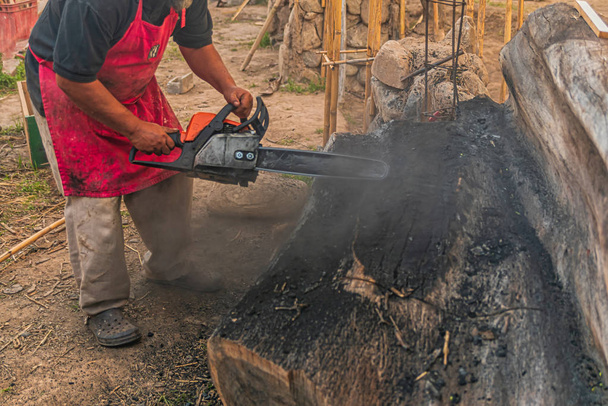 Fechar-se de velho moto-serra usando por trabalhador masculino descalço para cortar a árvore em dia ensolarado brilhante
 - Foto, Imagem