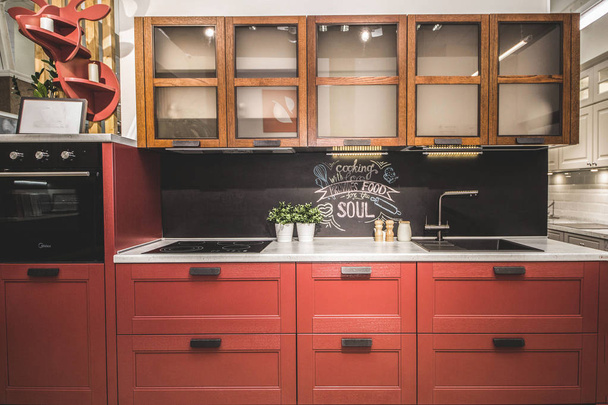Moderní červená kuchyně interiér s černými cihlovými zdmi, dřevěné desky s vestavěným umyvadlem a sporákem. - Fotografie, Obrázek