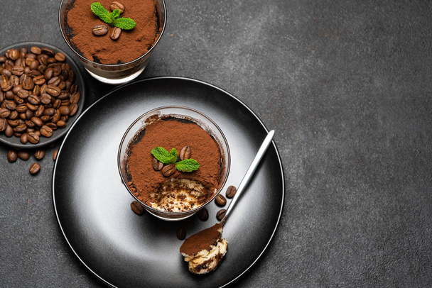 Portion of Classic tiramisu dessert in a glass cup on dark concrete background - Photo, Image