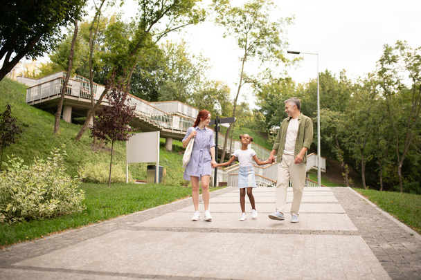 African-American girl walking in the park with parents - Foto, imagen