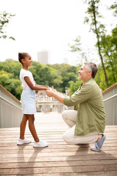 Loving father standing on his knee while talking to his daughter - Photo, Image
