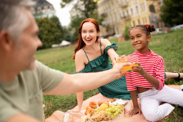 Adopted girl feeling amazing enjoying weekend picnic with parents - Foto, Bild