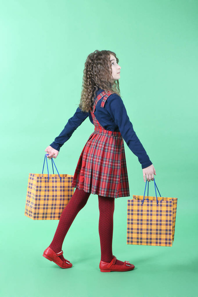 Kind mit einer gelben Verpackung kariert Textur isoliert auf grünem Hintergrund. Weihnachtsgeschenk, Einkaufen.  - Foto, Bild