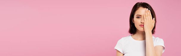 панорамный снимок красивой девушки, покрывающей лицо рукой, изолированной на розовом
 - Фото, изображение