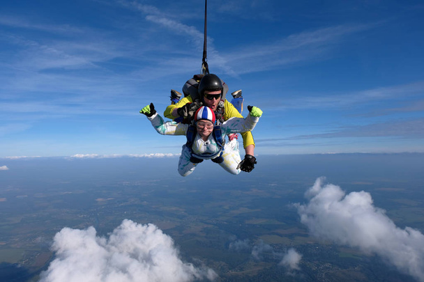 Tandem skydiving. Girl is flying in the sky with her instructor. - Photo, Image